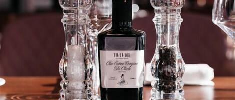 Una mesa servida con una botella de licor, saleros y pimenteros, y vasos.