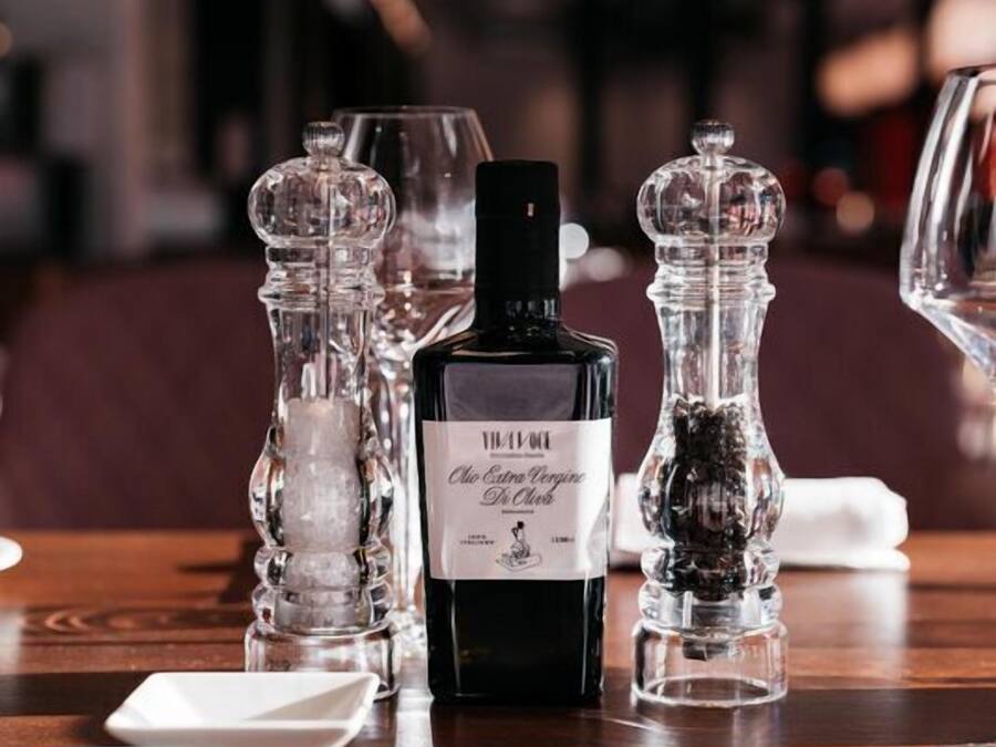 Una mesa servida con una botella de licor, saleros y pimenteros, y vasos.