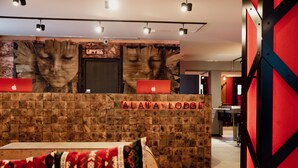 A reception desk with a wooden backdrop and a laptop, labeled "ALAVA LODGE". - Alaia Lodge (Crans-Montana)