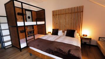 Un dormitorio con una cama individual superpuesta, una mesita de noche con lámpara y un cabecero de madera.