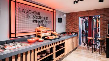 Zona de bufé con un cartel que dice “LAUGHTER IS BRIGHTEST WHERE FOOD IS BEST” y una variedad de alimentos expuestos en la barra.