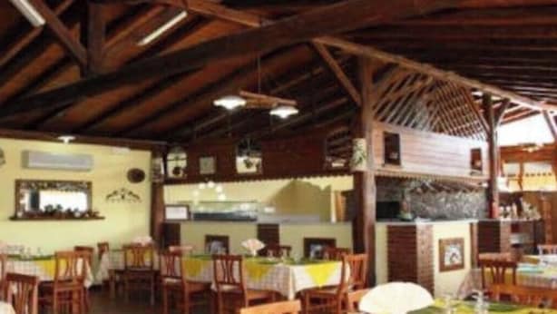 A restaurant with wooden beams, tables, and chairs. - Agriturismo Ghiritina (Francavilla di Sicilia)