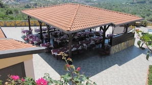 An outdoor patio area with tables and chairs, surrounded by a mountain landscape. - Agriturismo Ghiritina (Francavilla di Sicilia)