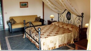A bedroom with a bed, a sofa, and a nightstand. - Agriturismo Ghiritina (Francavilla di Sicilia)