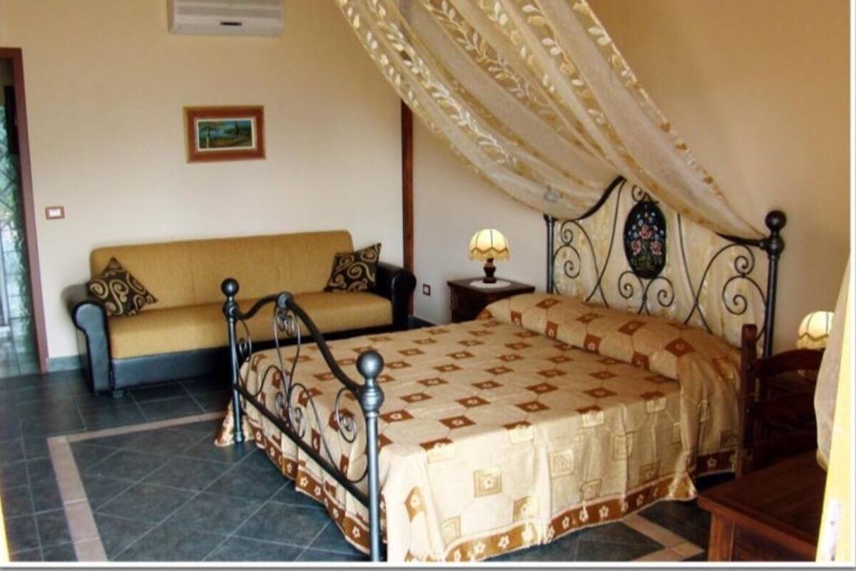 A bedroom with a bed, a sofa, and a nightstand.