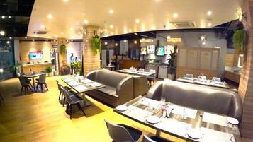 A restaurant with booths and tables, a counter, and a TV screen.