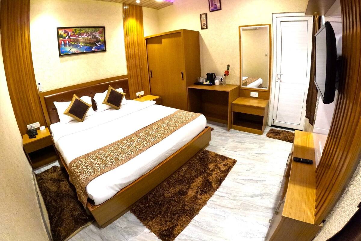 Une chambre d’hôtel moderne équipée d’un grand lit, d’un bureau, d’une armoire, d’un miroir et d’une télévision.