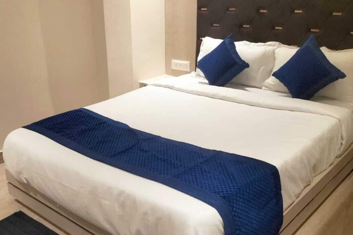 Un lit bien fait, avec du linge de lit blanc et un élément décoratif bleu.