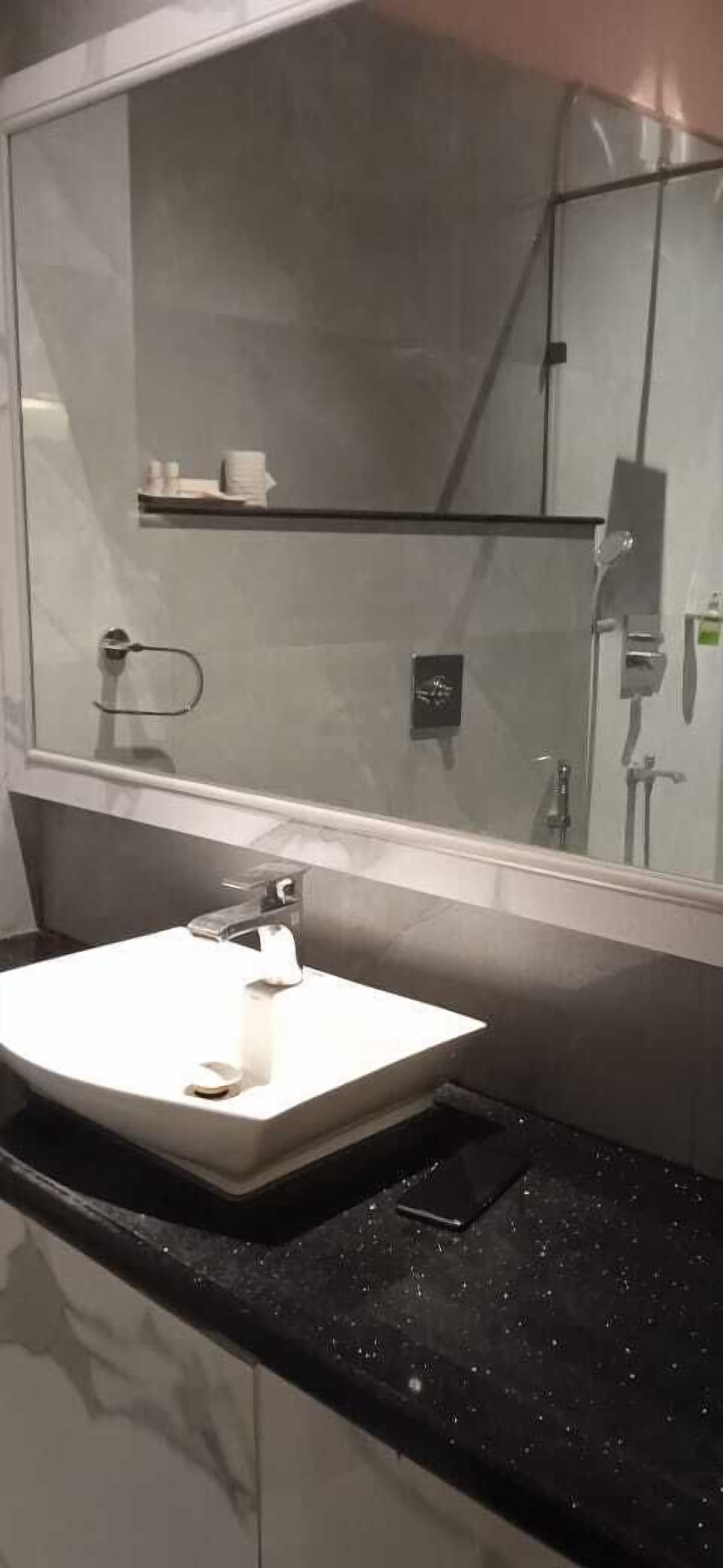 A bathroom with a white sink, a mirror, and a shower area.