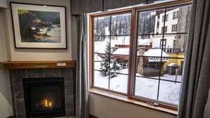 Una chimenea con un cuadro enmarcado encima, una ventana que ofrece vistas a un paisaje nevado, y un cartel que dice "MANTLES".