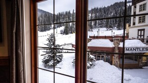 Vista desde una ventana de un paisaje cubierto de nieve, con un edificio identificado como "Mantles" en primer plano.
