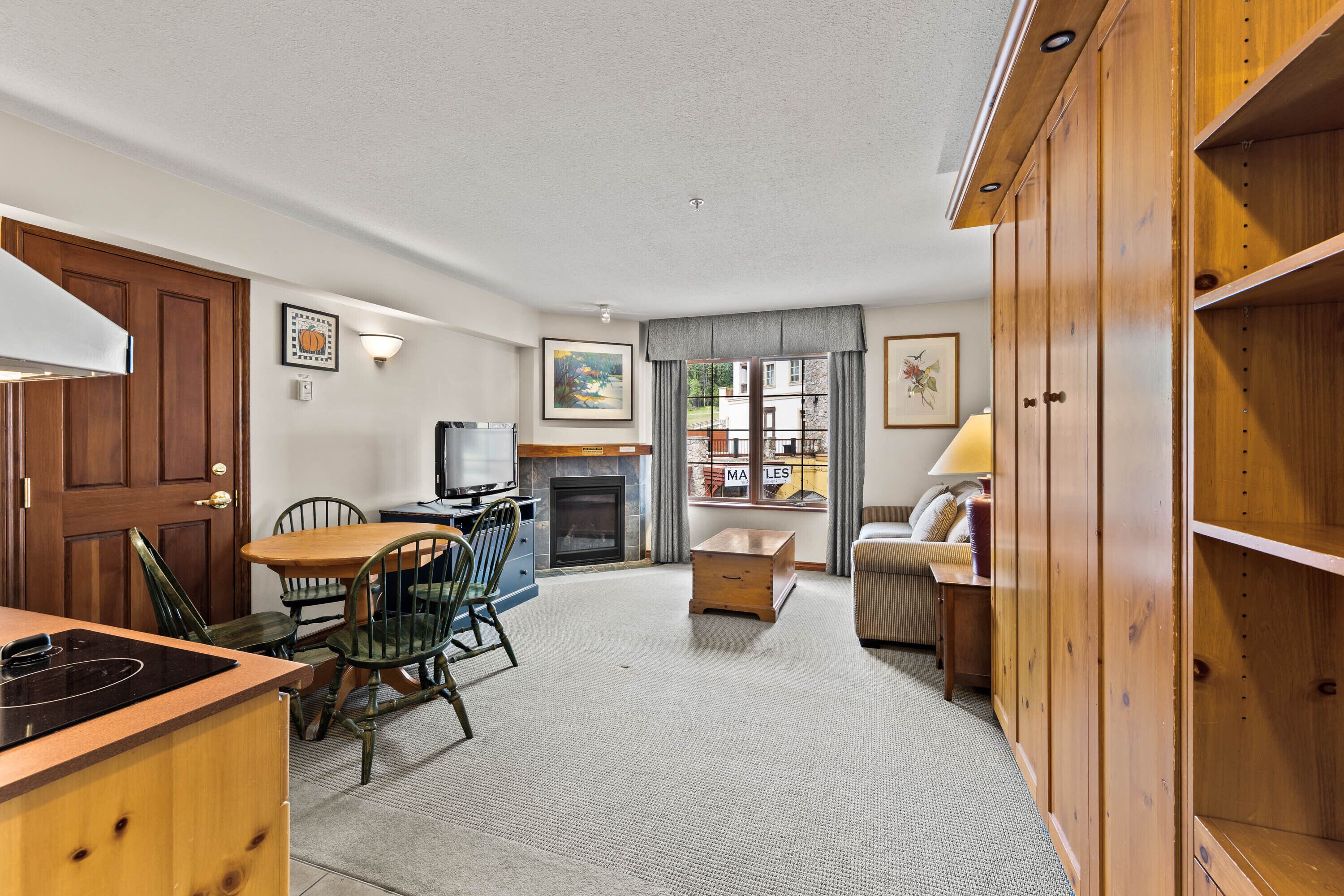 A compact living space with a dining area, kitchenette, and a fireplace.