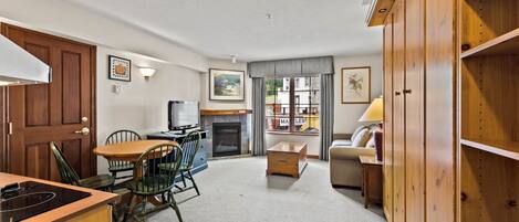 A compact living space with a dining area, kitchenette, and a fireplace.