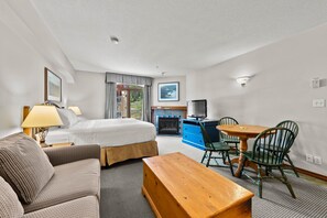 Una habitación de hotel con una cama, un sofá, una mesa de madera, un televisor y una chimenea.