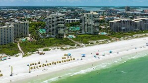 A coastal cityscape with high-rise buildings, a sandy beach, and a clear blue sky. - Beachfront 2BR/2BA Sandcastle condo with pool, WiFi, and heated pool (Marco Island)