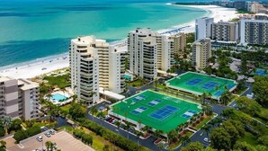 A coastal hotel with multiple high-rise buildings, a beach, and tennis courts. - Beachfront 2BR/2BA Sandcastle condo with pool, WiFi, and heated pool (Marco Island)