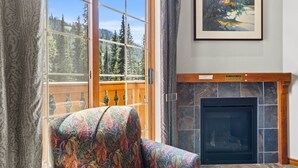Una habitación con un ventanal grande, una chimenea y un sillón de colores.