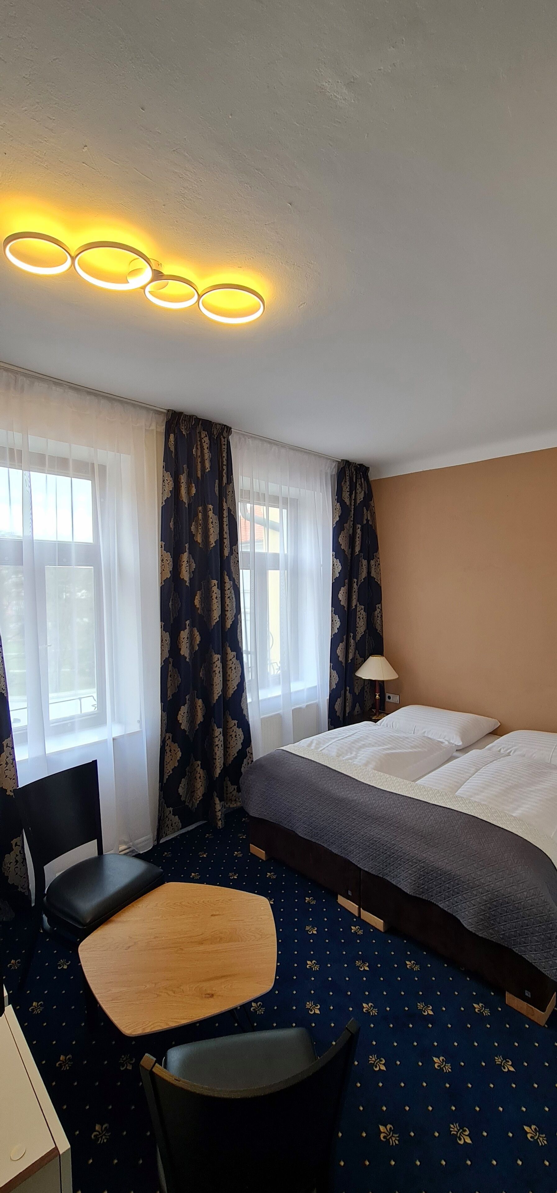 Una habitación de hotel con cama, escritorio, silla y lámpara.
