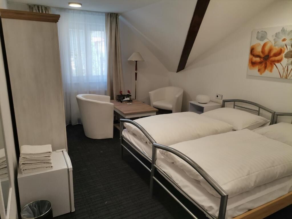 Une chambre d’hôtel avec deux lits, un bureau, une chaise, une lampe et un tableau au mur.