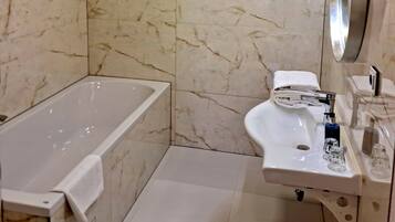 A bathroom with a bathtub, sink, and toilet. The walls are tiled with a marble pattern.