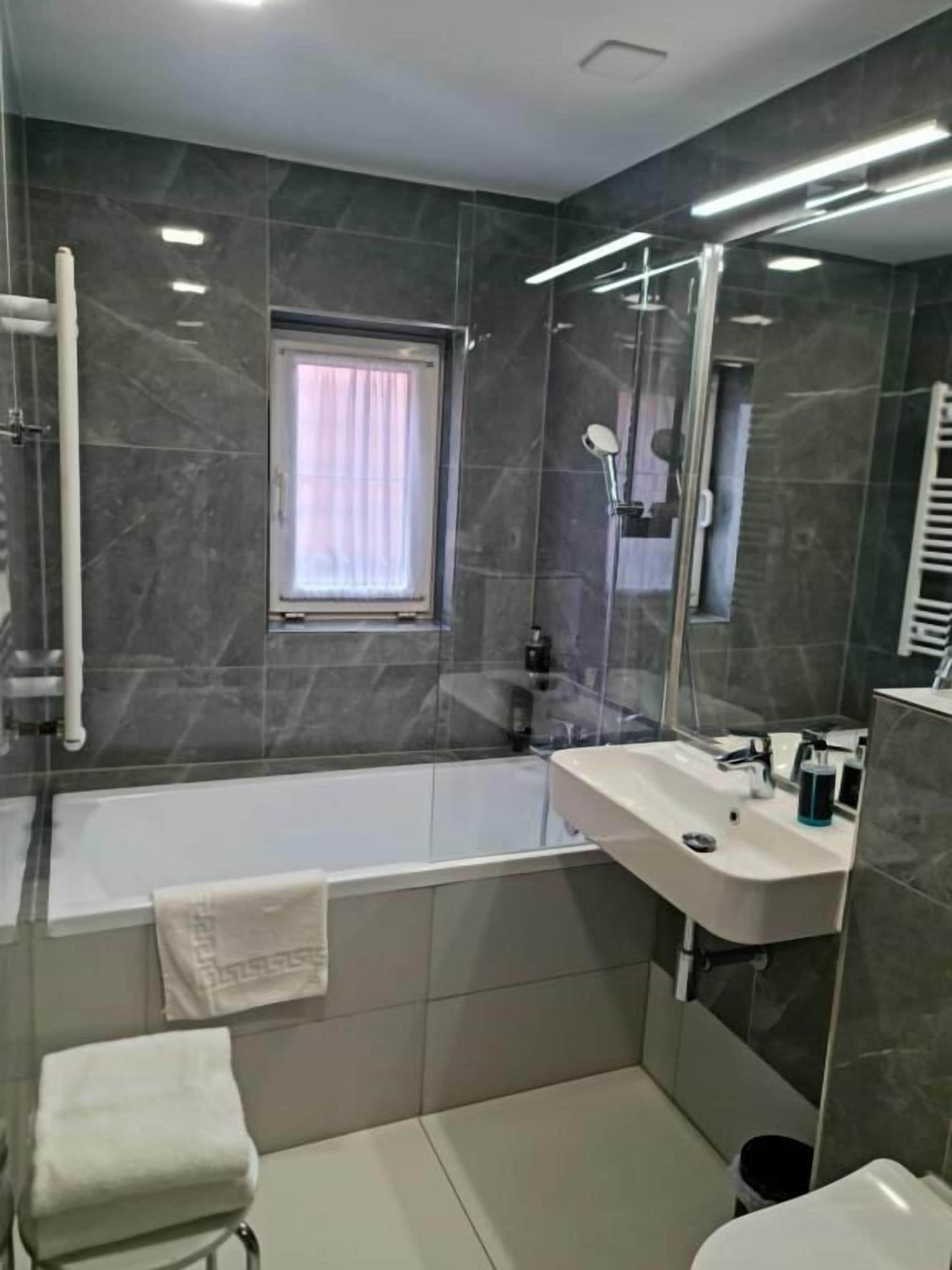 A modern bathroom with a bathtub, a sink, and a toilet.
