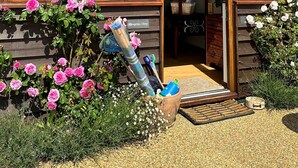 Un edificio de madera con ventanas amplias, una zona de recepción y un jardín con flores rosadas.