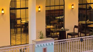 A restaurant with outdoor seating, large windows, and decorative lanterns.