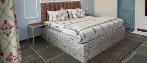 A bedroom with a bed, bedside tables, a wall-mounted air conditioner, and a door.