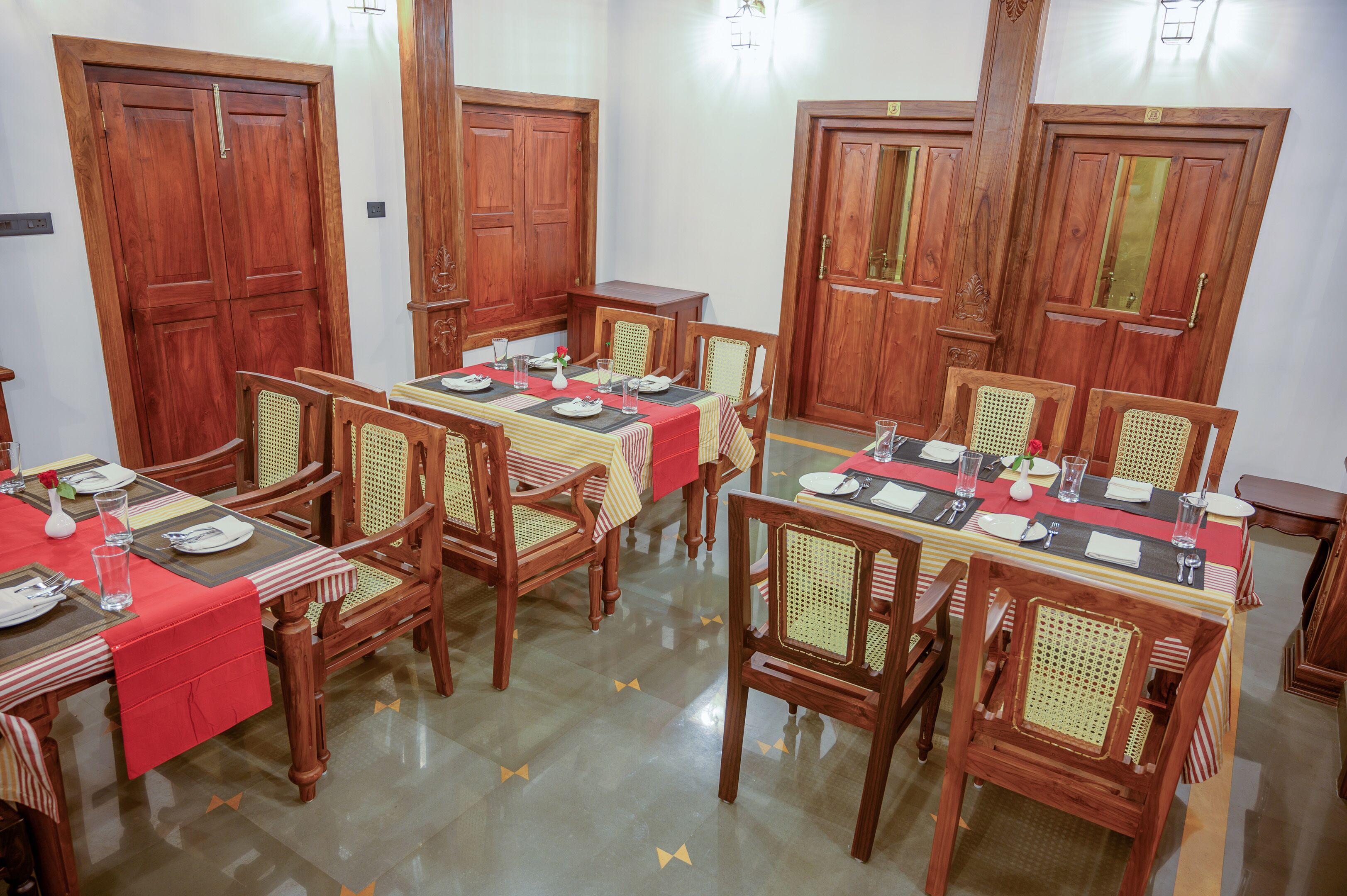 A dining area with wooden tables and chairs, equipped with table settings and glassware.
