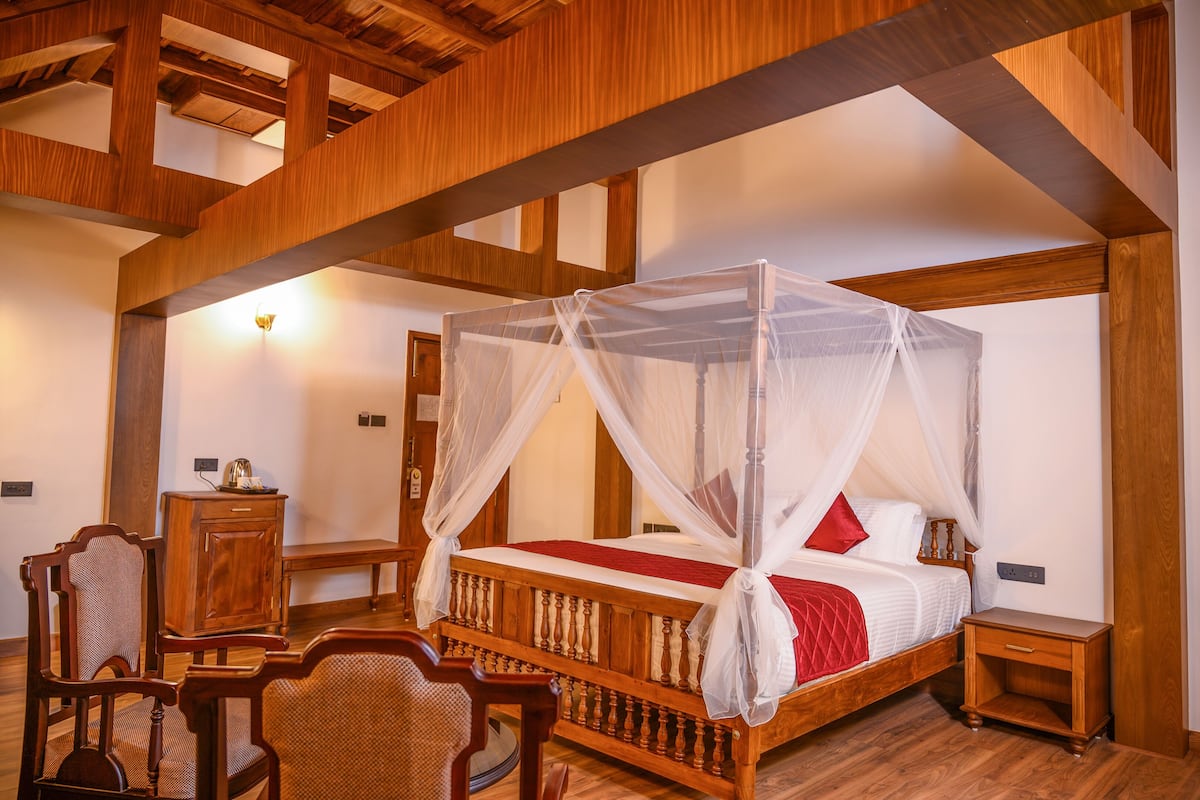 Una cama con dosel de madera, una mesita de noche de madera, una silla de madera y un mueble bajo.