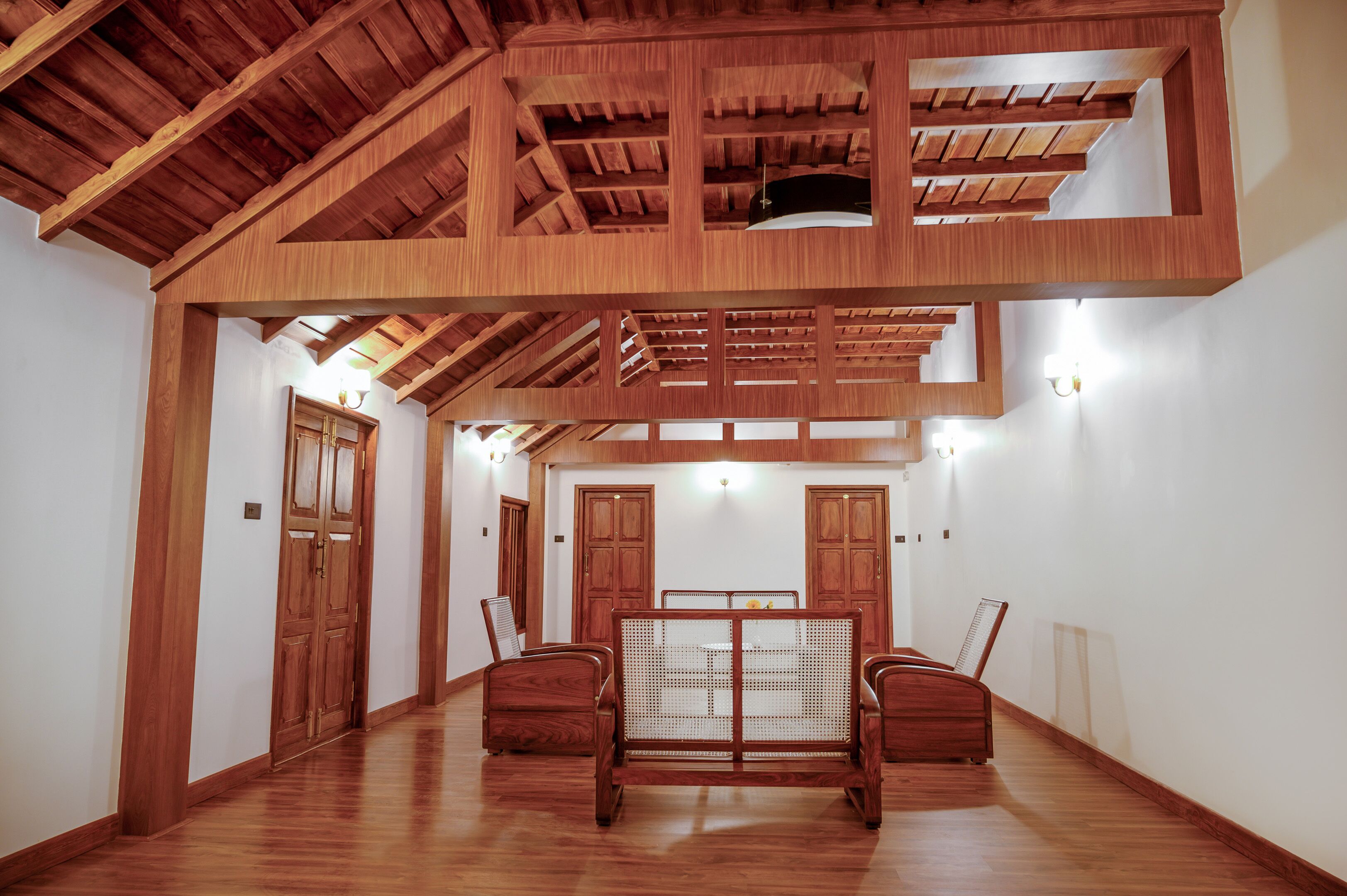 Una habitació àmplia amb terres de fusta, un sostre alçat amb bigues a la vista i una taula central amb cadires.