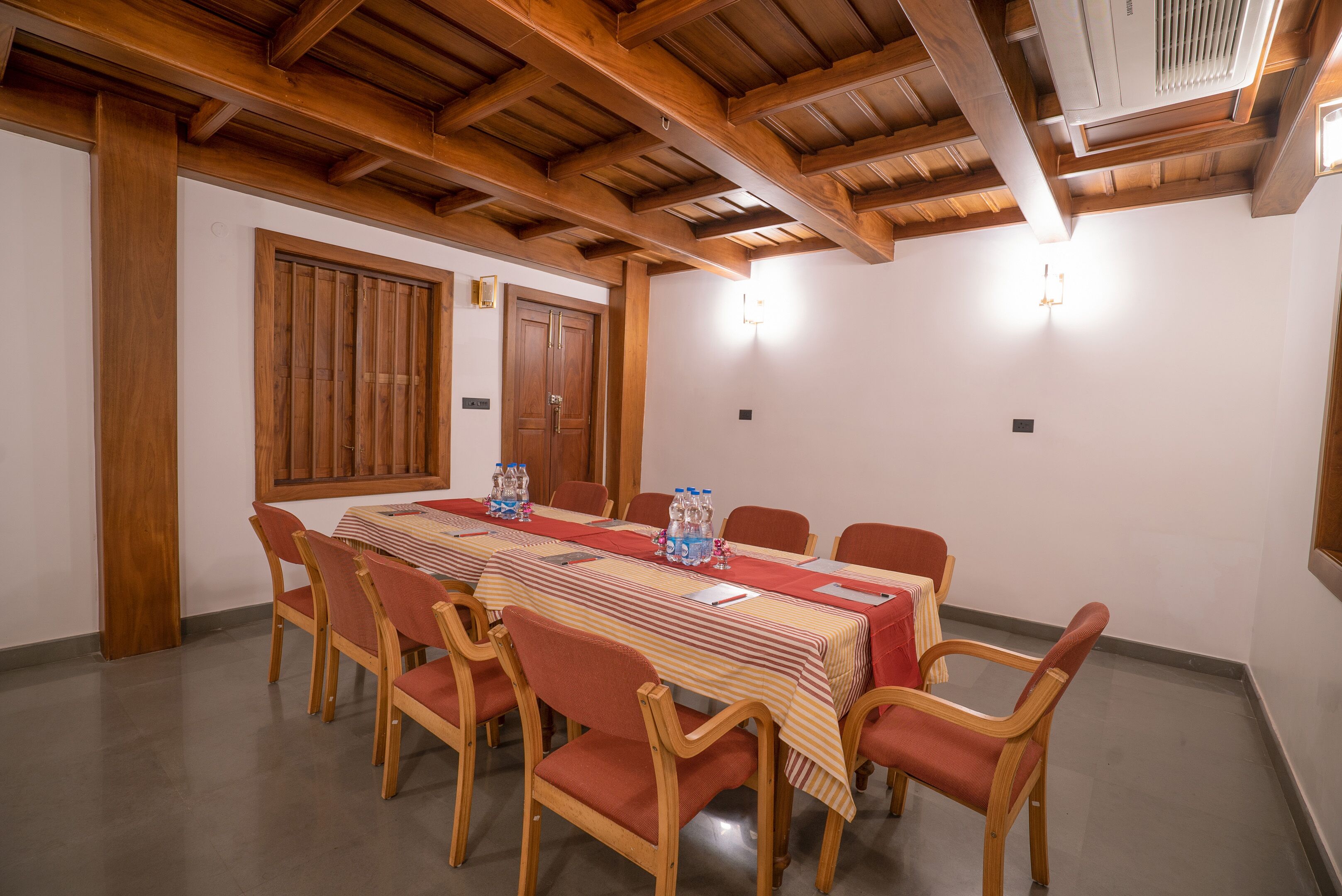 A conference room with a long table, wooden chairs, and a wooden ceiling.