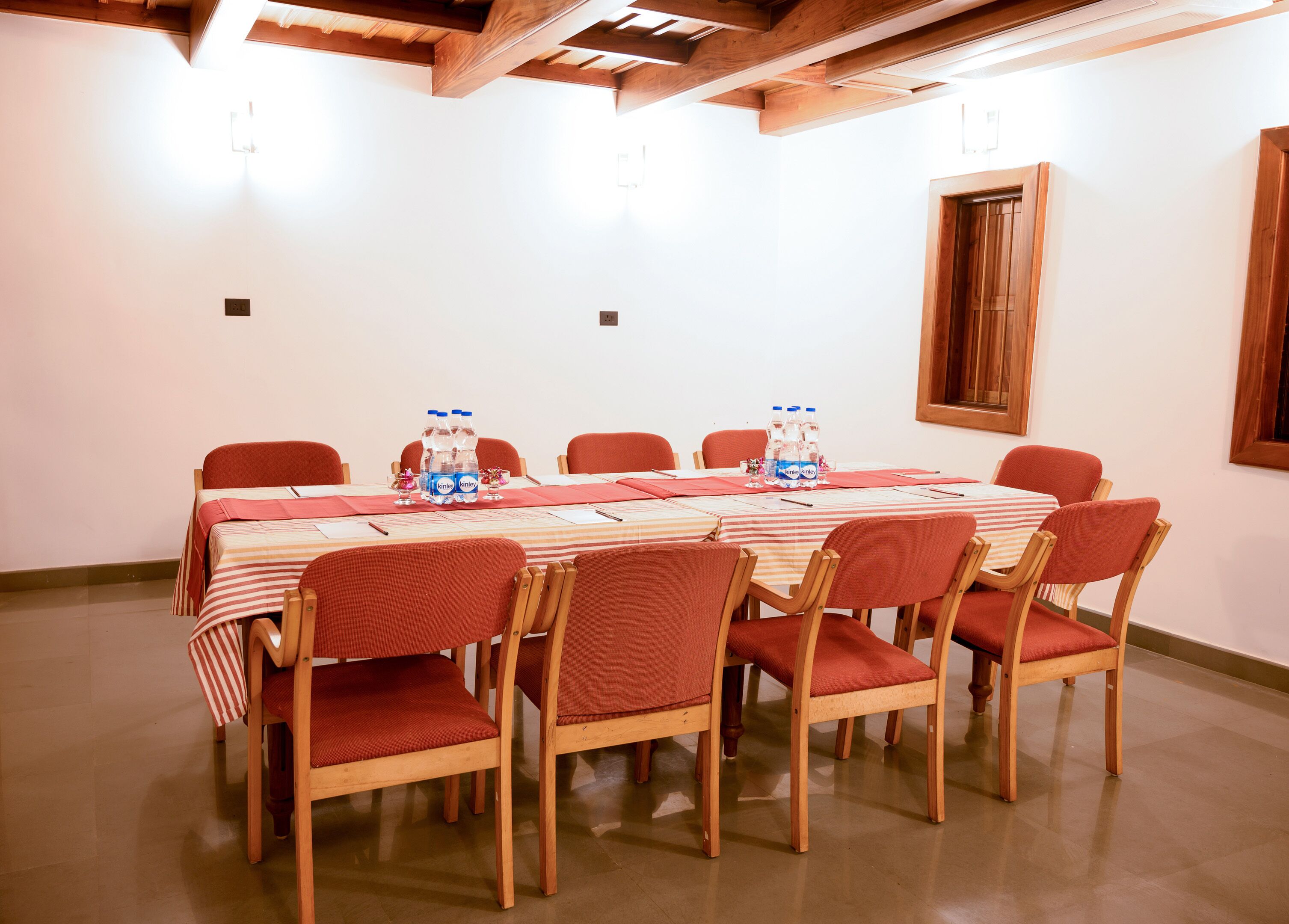 A conference room with a long table, red chairs, and water bottles on the table.