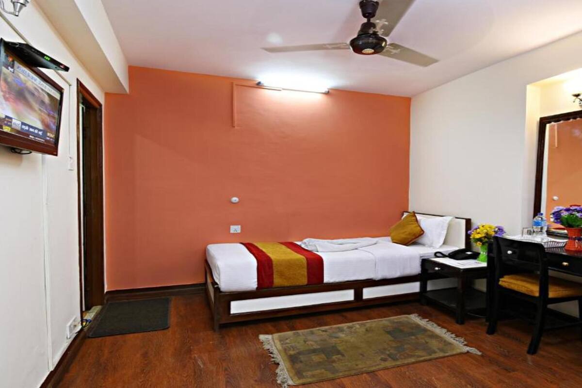 A bedroom with a bed, desk, chair, and a ceiling fan.