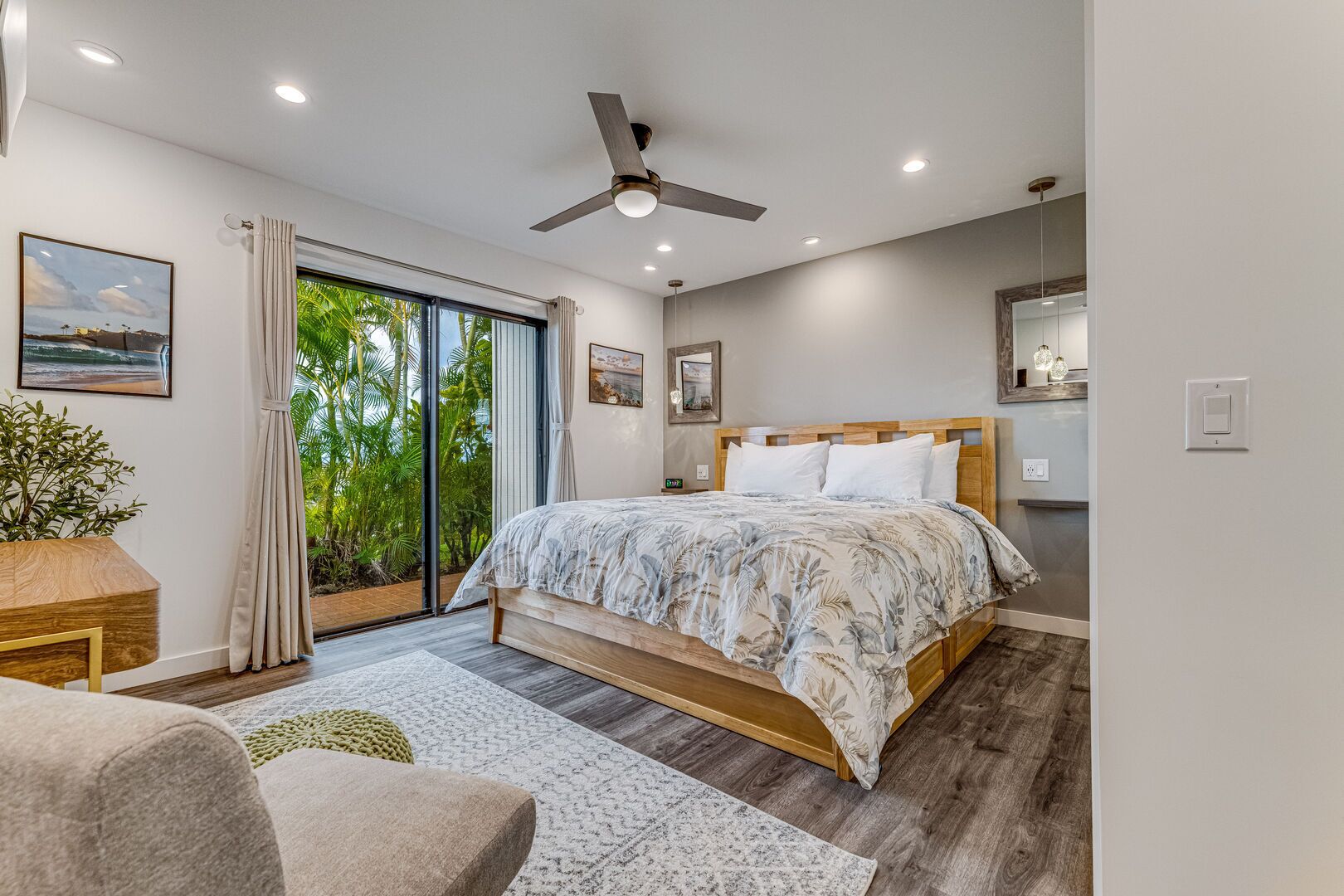 A modern bedroom with a large bed, a ceiling fan, and a sliding glass door leading to a balcony.