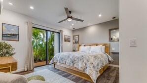 A modern bedroom with a large bed, a ceiling fan, and a sliding glass door leading to a balcony. - Wailea Ekolu – Oceanview in the Heart of Wailea (Kihei)