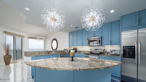 Una cocina moderna con armarios azules, electrodomésticos de acero inoxidable y una isla central.