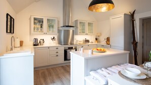 Une cuisine moderne avec des meubles blancs, des appareils en acier inoxydable et un îlot central doté de sièges.