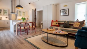 Un salon moderne avec un canapé, une table basse et un coin repas comprenant des chaises, et une cuisine en arrière-plan.