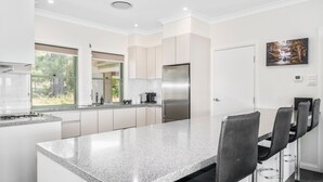 Eine moderne Küche mit Granit Arbeitsplatte, Edelstahlgeräten und einem Essbereich mit Barhocker.