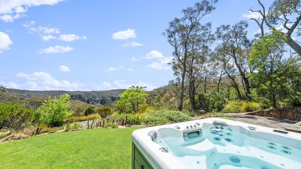 Ein Whirlpool in einem üppigen Garten mit Blick auf eine gebirgige Landschaft.