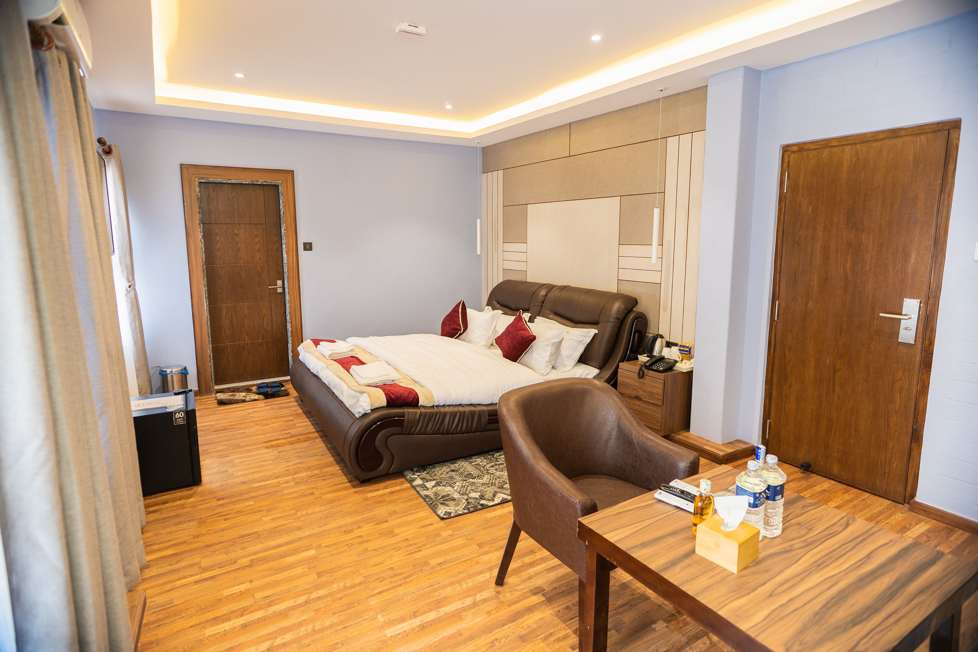 Quarto de hotel moderno com uma cama grande, uma escrivaninha de madeira e uma poltrona de couro.