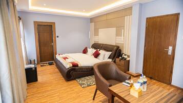 Quarto de hotel moderno com uma cama grande, uma escrivaninha de madeira e uma poltrona de couro.