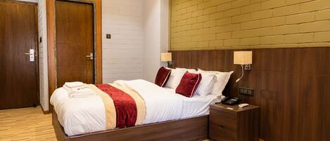 A neatly arranged bedroom with a wooden bed, a nightstand, and a wall-mounted lamp.