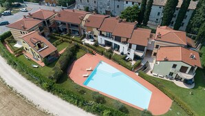 Una vista aerea di una zona residenziale con diverse case, una piscina e una strada.