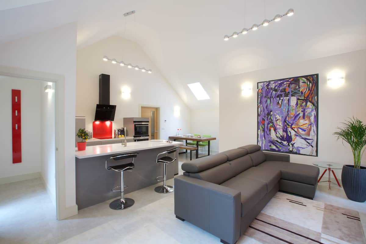 A modern kitchen with a central island, bar stools, and a dining area with a table and chairs.