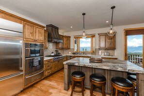 A modern kitchen with stainless steel appliances, wooden cabinets, and a large island with bar stools.