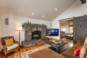 A living room with a stone fireplace, a television, and a sliding barn door.