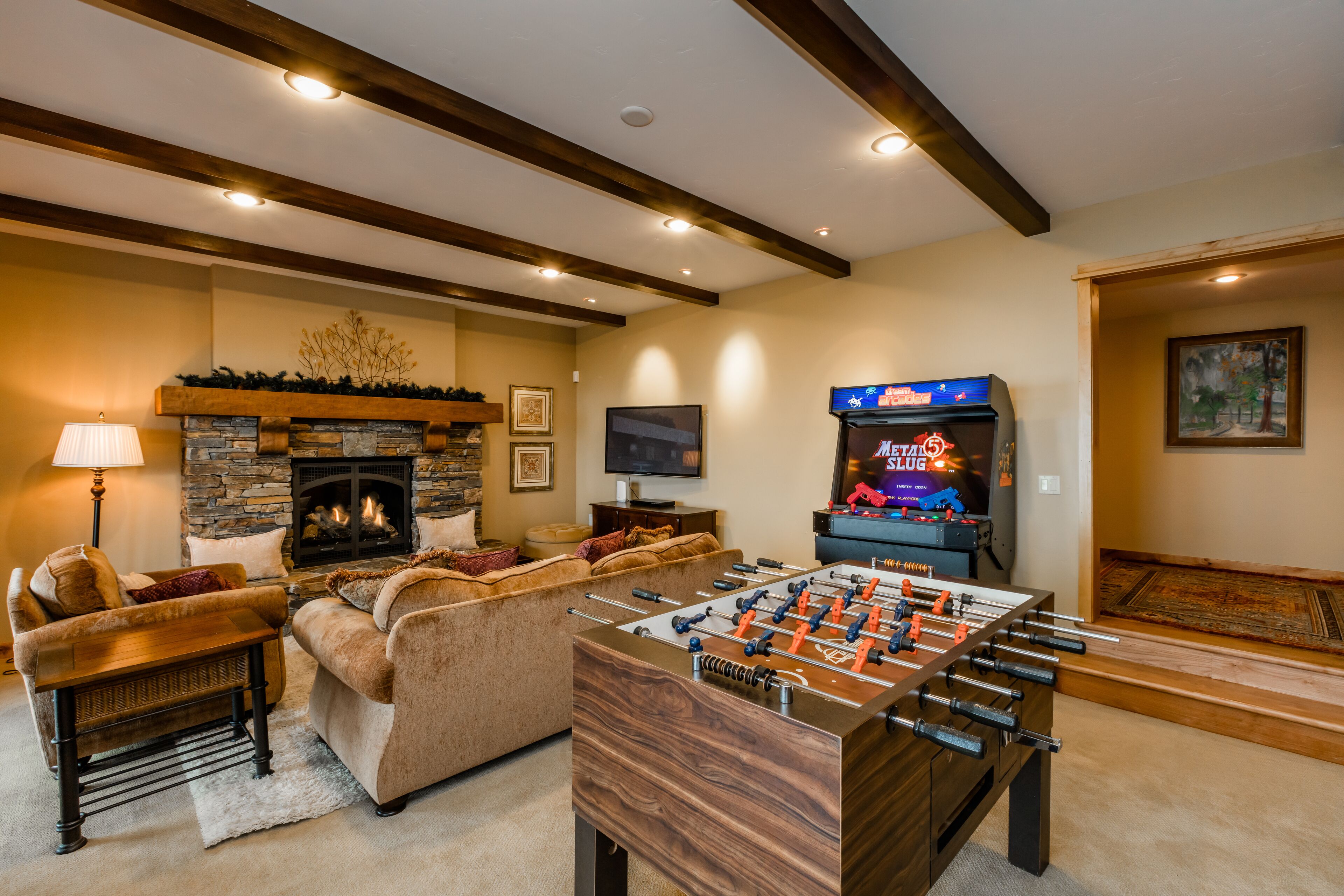 A cozy living room with a foosball table, a fireplace, and a television.