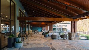 An outdoor patio area with stone flooring, wooden beams, and seating arrangements.